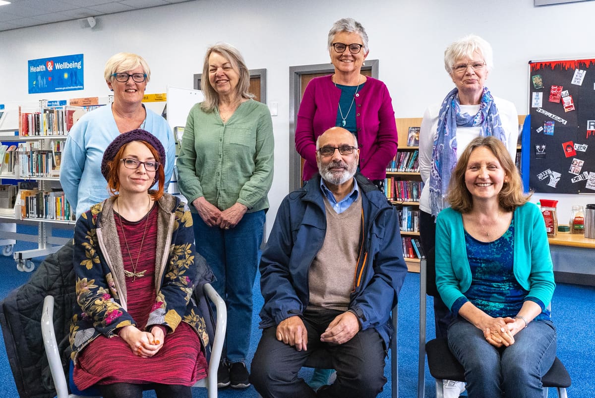 Members of a shared reading group seated together in a library
